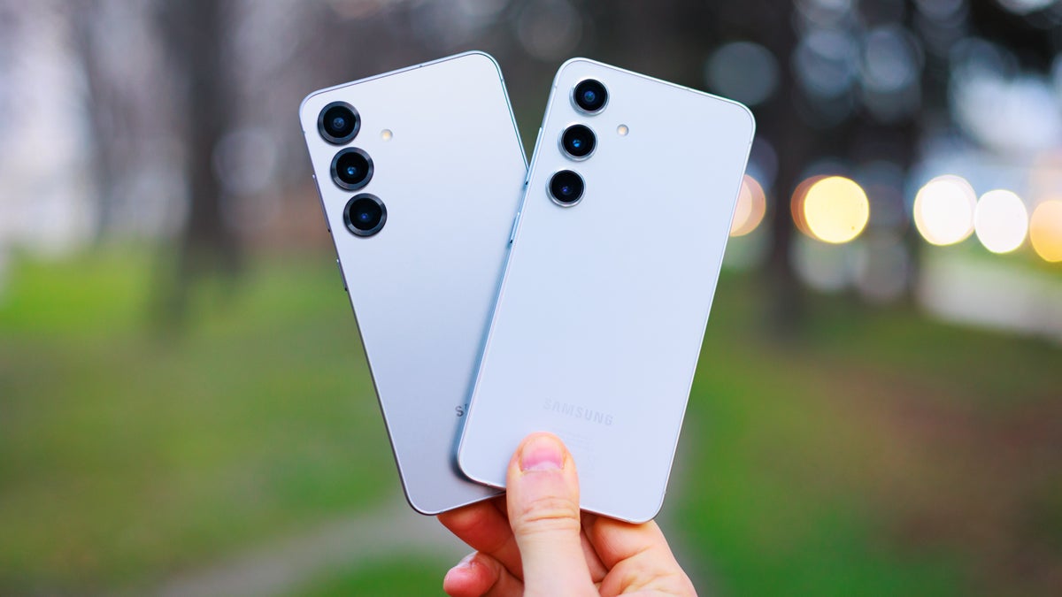 Hand holding two phones spread like a fan, backs facing the camera.