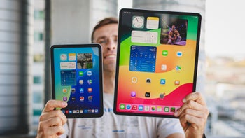 Person holding iPad mini and the huge iPad Air 13", displays towards the camera, homescreens and wallpapers are visible