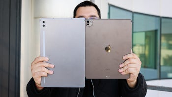 Man holding the Galaxy Tab S10 Ultra and iPad Pro 13" M4 up. The tablets are so large, they cover almost the entire image