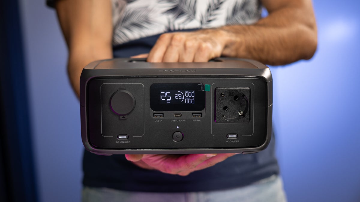 A person holds the EcoFlow River 3, showcasing its front design with ports and LCD display.