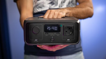 A person holds the EcoFlow River 3, showcasing its front design with ports and LCD display.