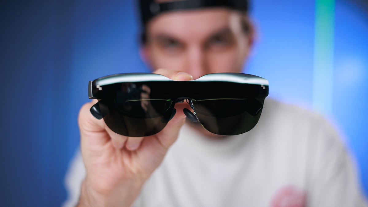 A person holding the RayNeo Air 3s in their hand, facing the viewer.