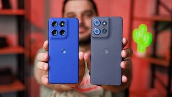 Hands holding two phones, showing their backs to camera.