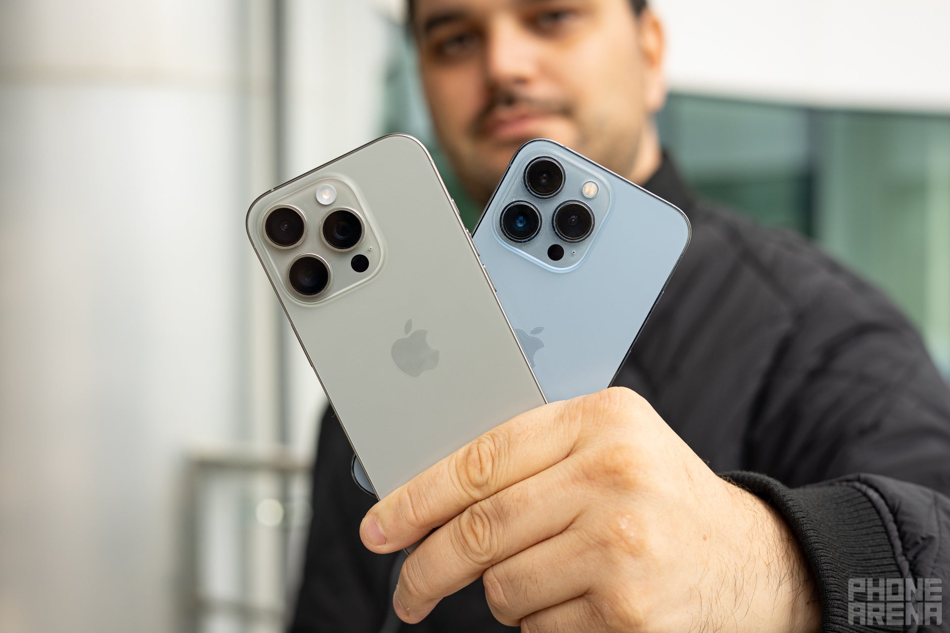 A man holding Apple iPhone 16 Pro next to the iPhone 13 Pro