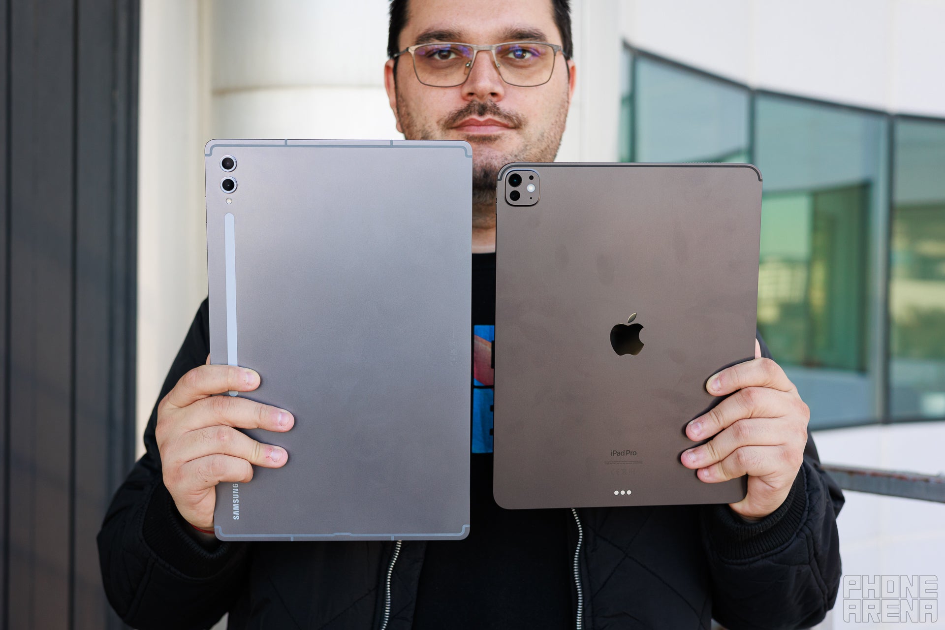 Galaxy Tab S10 Ultra and iPad Pro M4 13&amp;quot; held by a person, the backs of the devices are towards the camera