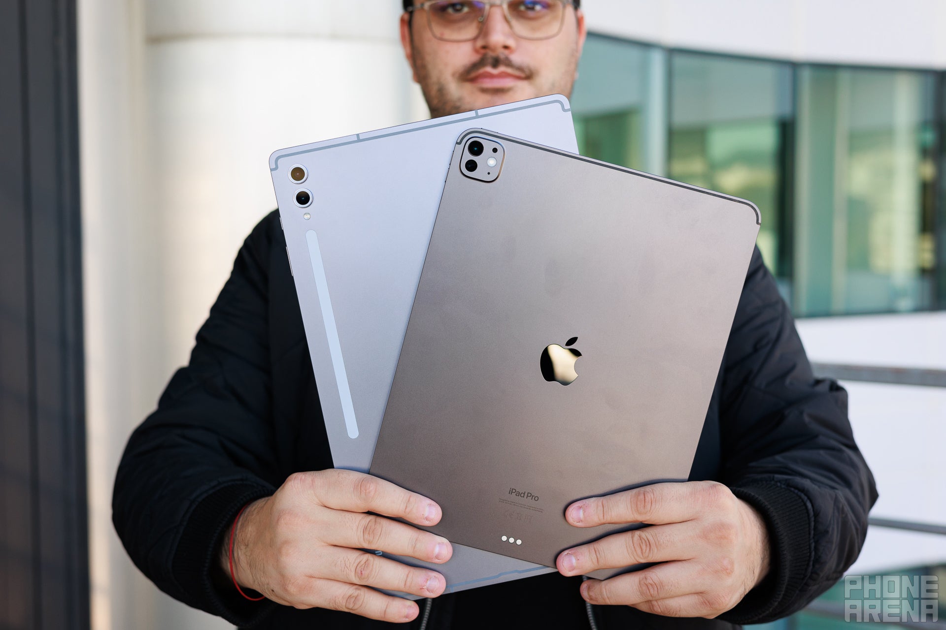 Galaxy Tab S10 Ultra and iPad Pro M4 13&amp;quot; held by a person, the backs of the devices are towards the camera