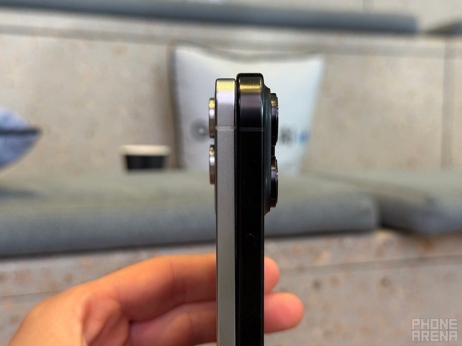 Galaxy S25 Edge and iPhone 16 Pro Max standing on table, pictured from the side